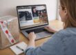 Woman bidding in a live online auction in South Africa, viewing auction lot on laptop with packaged item on desk