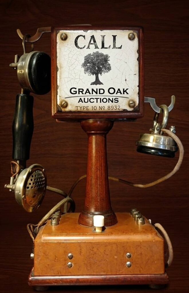 Antique wooden telephone featuring a "Call Grand Oak Auctions" sign for professional auctioneer services and valuations in Johannesburg.